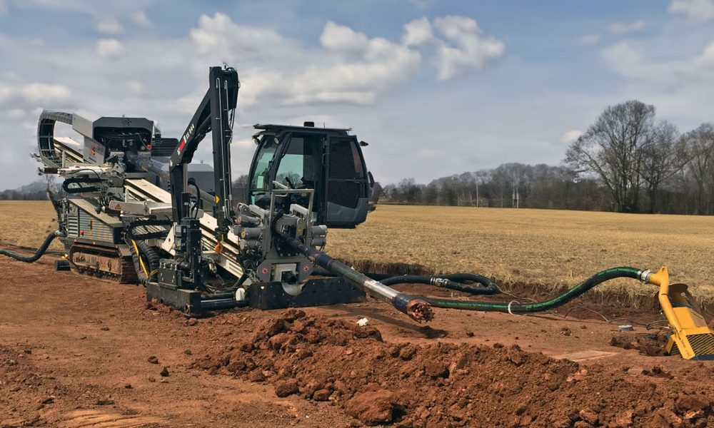 Specialized drilling machinery operating on a rural landscape with open fields in the background.